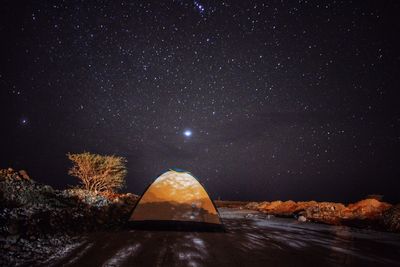 Tent on land against star field at night