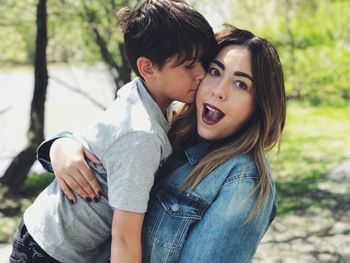 Portrait of boy kissing mother while standing outdoors