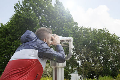 Rear view of man with arms raised against trees