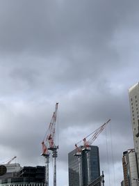 Low angle view of cranes at construction site against sky