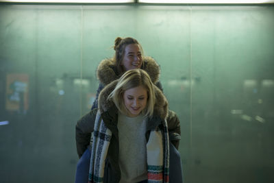 Young woman giving piggyback to friend 