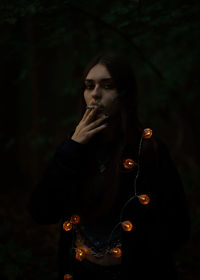 Portrait of young woman smoking in dark