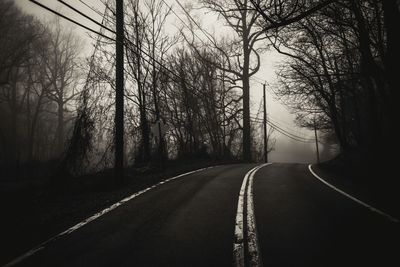 Empty road amidst trees against sky