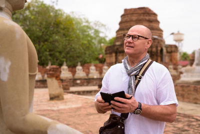 Man holding camera while standing on mobile phone