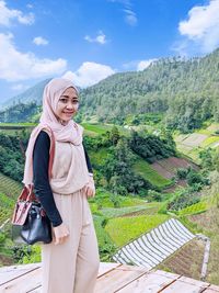 Portrait of smiling young woman standing on mountain