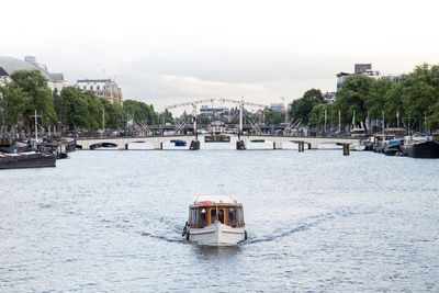 Sailboat in river against sky in city