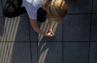 High angle view of woman photographing with mobile phone on street