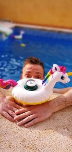 Portrait of man holding inflatable toy in swimming pool