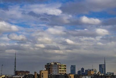 Buildings in city against cloudy sky