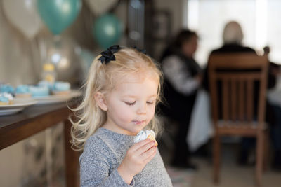 Cute girl eating cupcake at home during birthday party