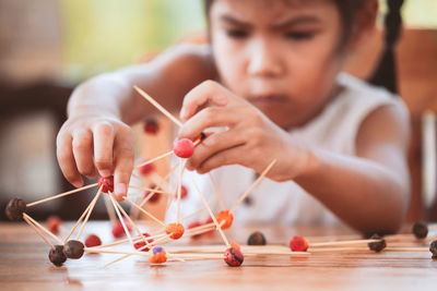 Cute girl making molecule model on wooden table in porch