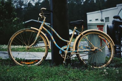 Bicycle parked on grass against tree trunk