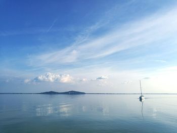 View of boat in calm sea against cloudy sky