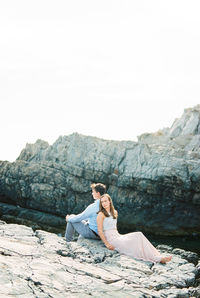 Young woman sitting on rock against mountain