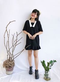 Portrait of young woman standing against wall