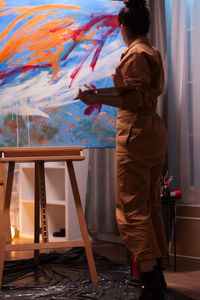 Rear view of woman painting at home