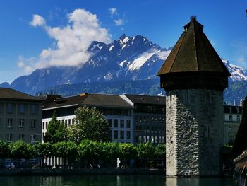 Built structure by lake and buildings against sky