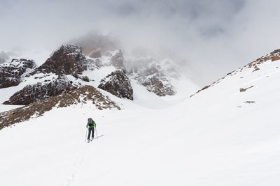 Skier touring in backcountry towards foggy mountain