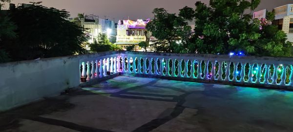 View of swimming pool by building at night