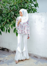 Midsection of woman standing against white wall