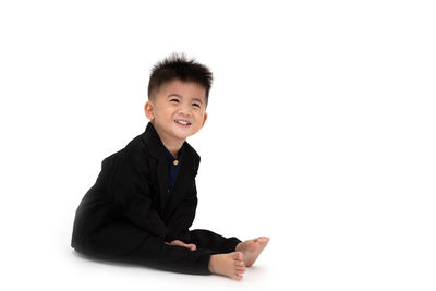 Portrait of smiling boy sitting against white background