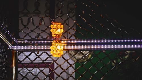 Illuminated chainlink fence against sky at night