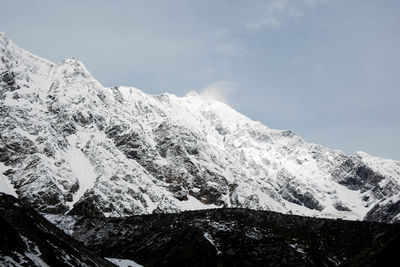 Low angle view of snowcapped mountains against sky