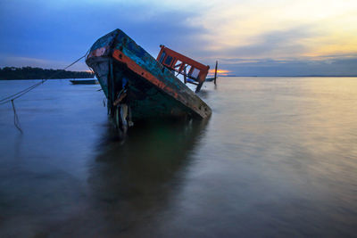 Abandoned boat in sea against sky