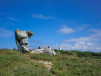 Statue on field against sky