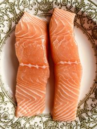 Close-up of two fresh salmon fillets. pinky orange fish. in an ornate green and white ceramic dish.