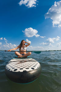 Rear view of woman jumping in sea against sky