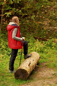 Side view of a woman holding plant in forest