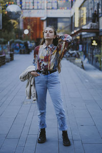 Full length of young woman standing on footpath