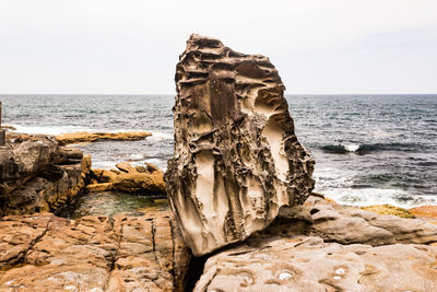 Rock formation on beach against sky