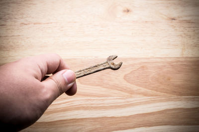 Close-up of hand holding old rusty spanner