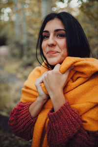 Close-up of smiling young woman looking away while standing in forest during winter