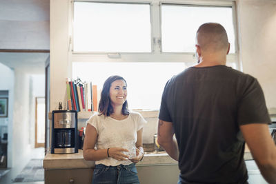 Happy woman looking at man in kitchen