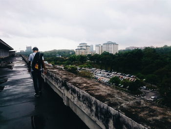 Woman standing by railing against sky