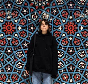 Portrait of young man standing against wall