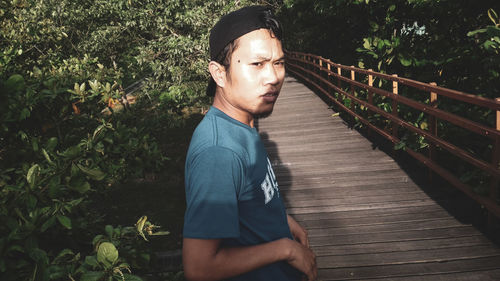 Portrait of young man standing on footbridge