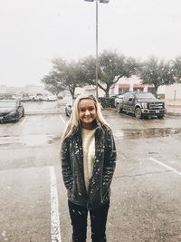 Portrait of smiling young woman standing in car