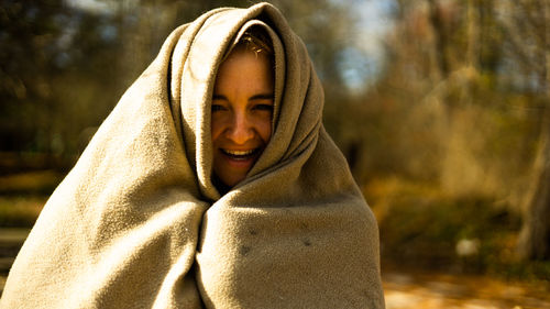 Portrait of young woman standing against trees
