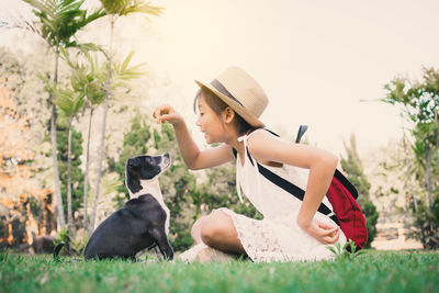 Girl playing with dog on grassy field at park