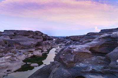 Rock formations in sea against sky during sunset