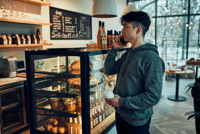 Young man talking on the phone at cafe, having a important phone call, answering call, chatting