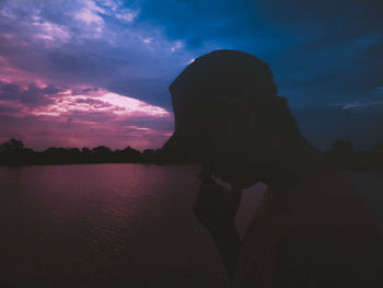 Portrait of silhouette woman by lake against sky during sunset