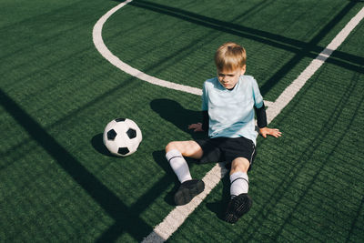 Full length of boy playing soccer ball on grass