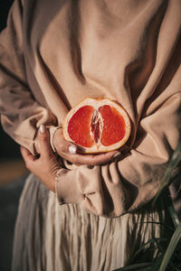 Midsection of woman holding fruit