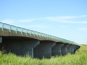 Bridge over grassy field against sky