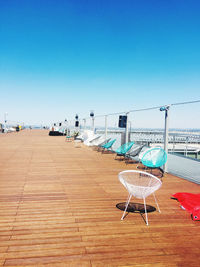Empty chairs against clear blue sky